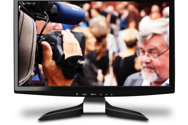 Fernseher mit Politiker vor Mikrofon in Farbe